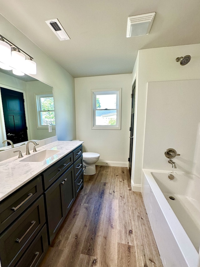 full bathroom with wood-type flooring, vanity, toilet, and a wealth of natural light