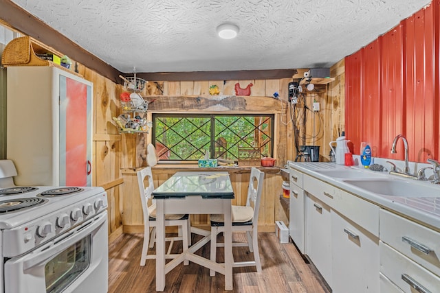 kitchen featuring white cabinets, wooden walls, hardwood / wood-style floors, white electric range oven, and a textured ceiling