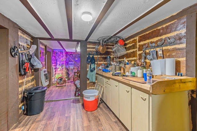 interior space with a textured ceiling, wood walls, hardwood / wood-style floors, wooden counters, and heating unit