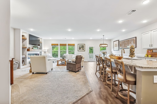 living room with light wood-type flooring, a fireplace, and sink