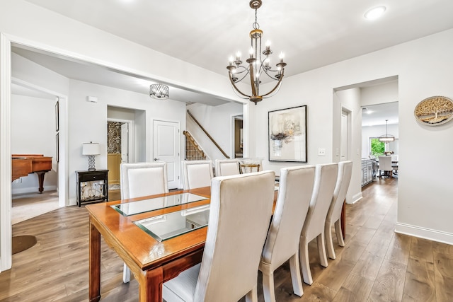 dining area with wood-type flooring and an inviting chandelier