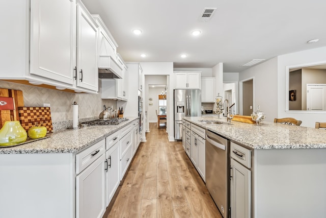 kitchen featuring white cabinetry, tasteful backsplash, stainless steel appliances, light hardwood / wood-style flooring, and sink