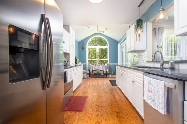 kitchen with light wood-type flooring, vaulted ceiling, white cabinetry, and stainless steel appliances