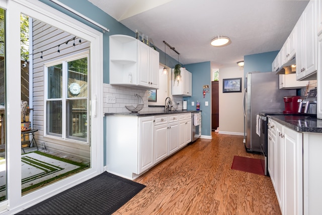 kitchen featuring light wood-type flooring, appliances with stainless steel finishes, white cabinets, and pendant lighting