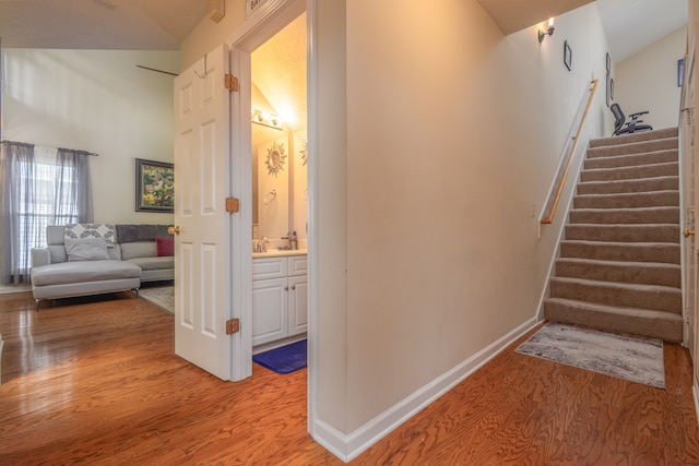 stairway featuring lofted ceiling and wood-type flooring