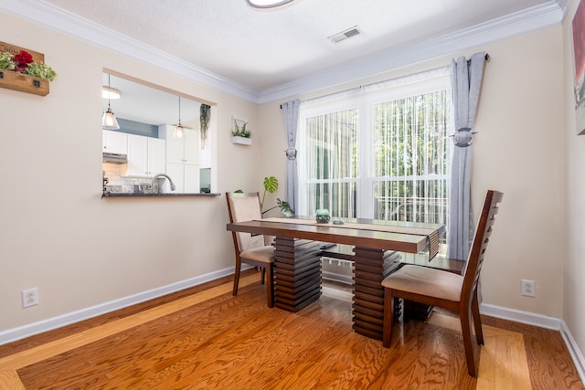 dining space featuring a textured ceiling, ornamental molding, sink, and wood-type flooring