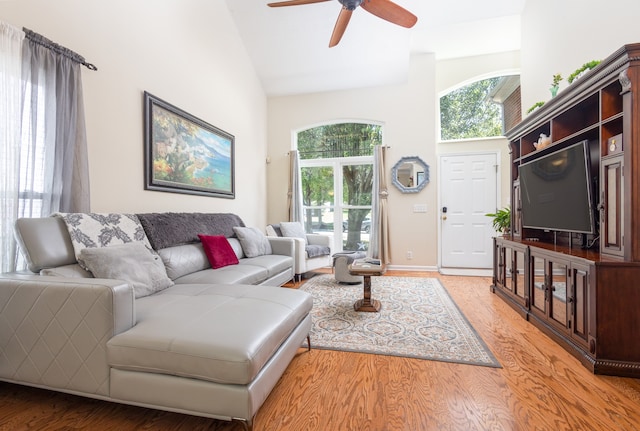 living room featuring ceiling fan, high vaulted ceiling, and light hardwood / wood-style floors