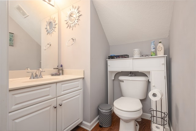 bathroom featuring toilet, hardwood / wood-style floors, vanity, a textured ceiling, and lofted ceiling