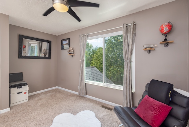 living area featuring light carpet and ceiling fan