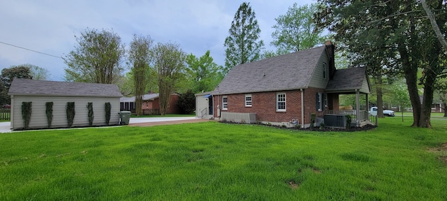 view of side of home featuring cooling unit, a lawn, and a storage unit