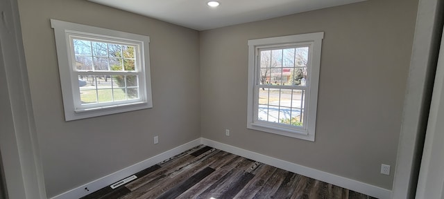 unfurnished room featuring a wealth of natural light and dark hardwood / wood-style floors