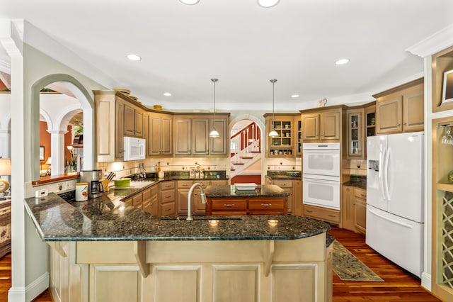 kitchen featuring decorative light fixtures, white appliances, dark wood-type flooring, kitchen peninsula, and sink