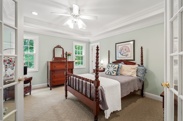 carpeted bedroom featuring a raised ceiling, ceiling fan, and ornamental molding