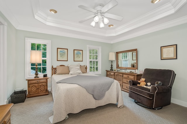 bedroom featuring a tray ceiling, light carpet, ornamental molding, and ceiling fan