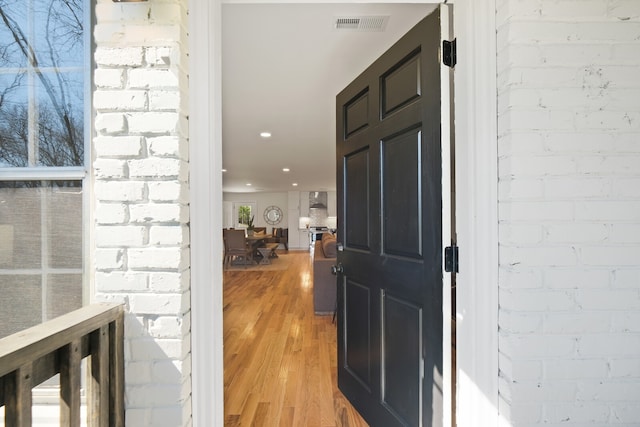 foyer entrance with hardwood / wood-style flooring and brick wall