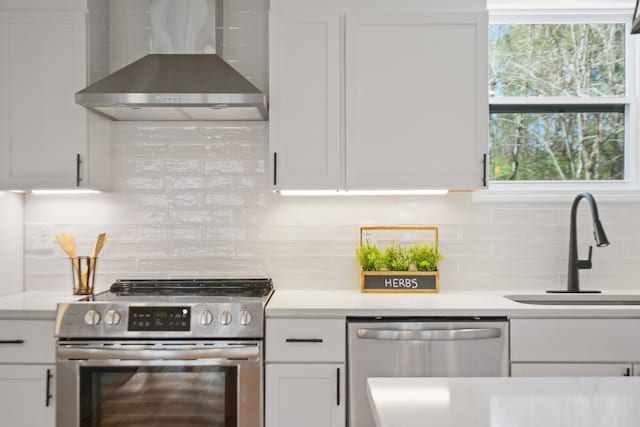 kitchen featuring stainless steel appliances, wall chimney exhaust hood, white cabinets, and tasteful backsplash