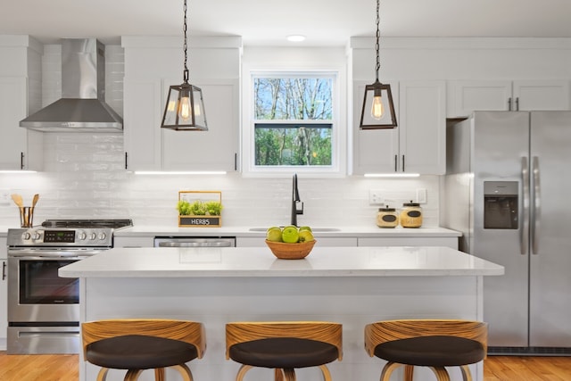 kitchen featuring white cabinetry, wall chimney range hood, appliances with stainless steel finishes, and sink