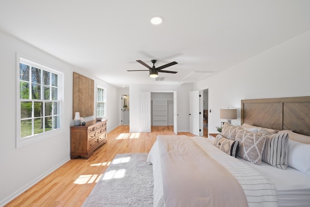 bedroom with light wood-type flooring, a spacious closet, and ceiling fan