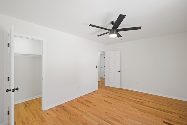 unfurnished bedroom featuring a closet, light hardwood / wood-style floors, a spacious closet, and ceiling fan