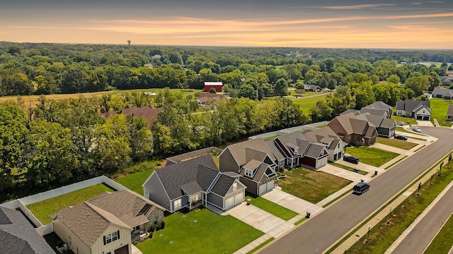 aerial view at dusk featuring a residential view and a view of trees