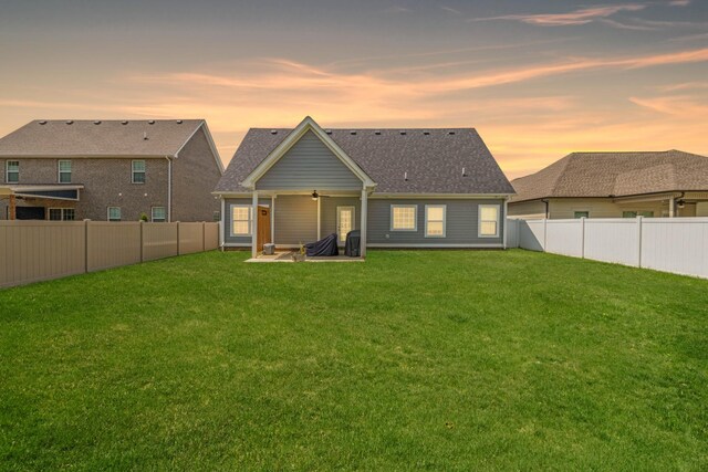 back of house featuring a shingled roof, a patio area, a fenced backyard, and a yard