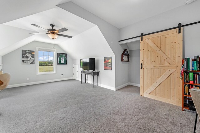 additional living space featuring ceiling fan, a barn door, carpet flooring, baseboards, and vaulted ceiling