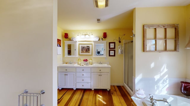 bathroom featuring hardwood / wood-style floors, vanity, and plus walk in shower