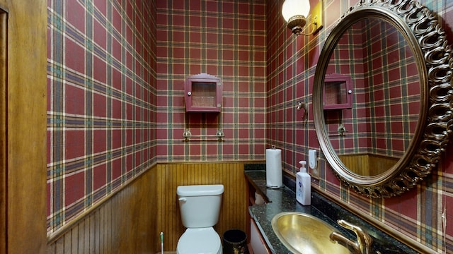 bathroom featuring wood walls, toilet, and sink