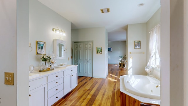 bathroom with a tub to relax in, vanity, and wood-type flooring