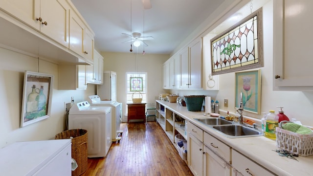 clothes washing area with cabinets, sink, ceiling fan, wood-type flooring, and washer and dryer