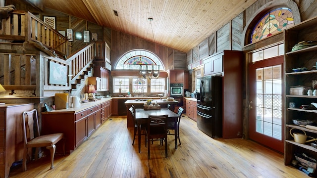 kitchen with wood ceiling, black refrigerator, wooden walls, high vaulted ceiling, and light wood-type flooring