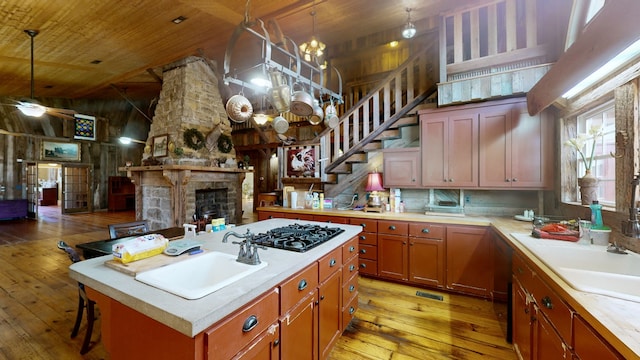 kitchen featuring a stone fireplace, white gas stovetop, high vaulted ceiling, a kitchen island, and light wood-type flooring