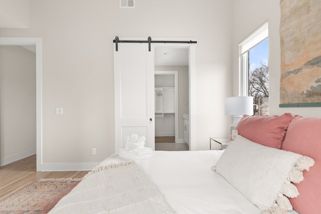 bedroom featuring hardwood / wood-style flooring, a walk in closet, a barn door, and a closet