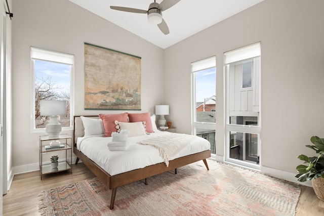 bedroom with light hardwood / wood-style flooring, multiple windows, ceiling fan, and vaulted ceiling