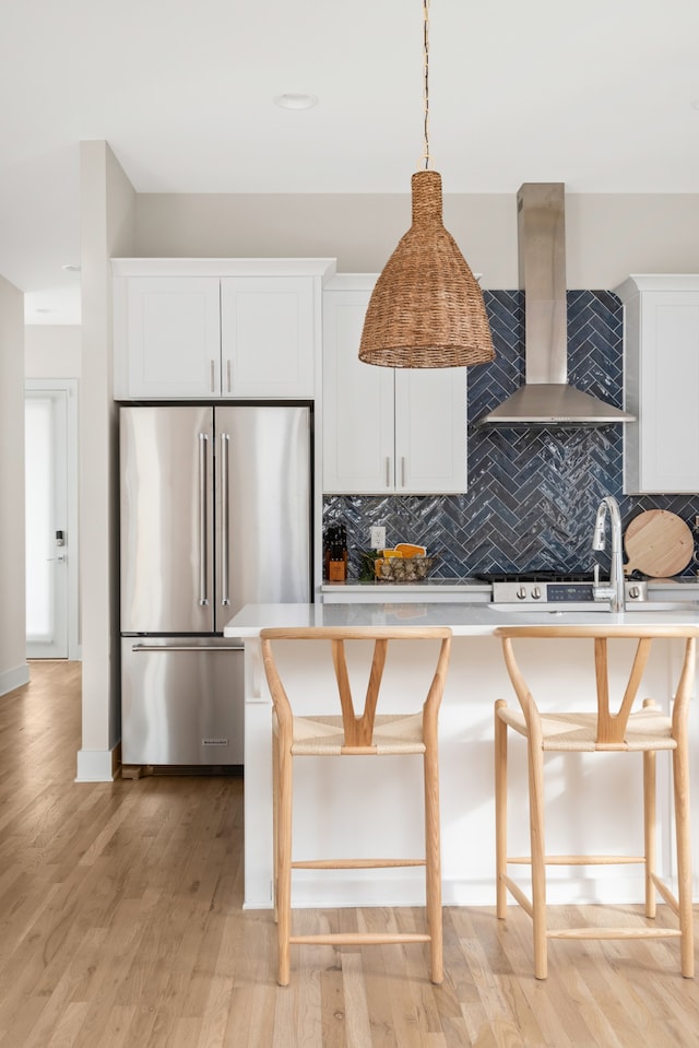 kitchen featuring light hardwood / wood-style flooring, high end refrigerator, backsplash, and white cabinets