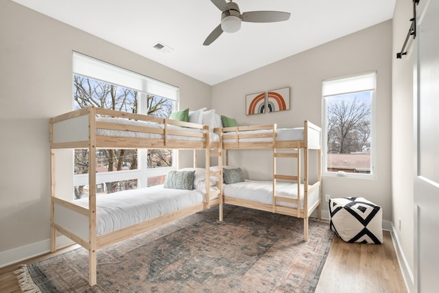 bedroom with multiple windows, ceiling fan, vaulted ceiling, and light hardwood / wood-style flooring