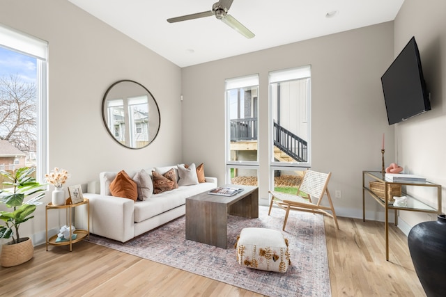 living room with light wood-type flooring, ceiling fan, and a healthy amount of sunlight