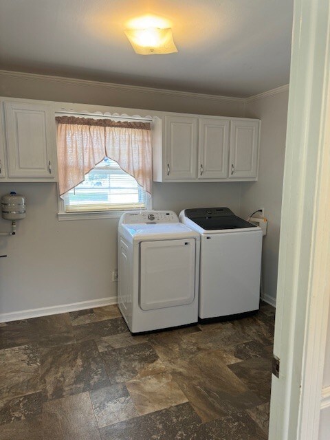 washroom with ornamental molding, washing machine and clothes dryer, and cabinets