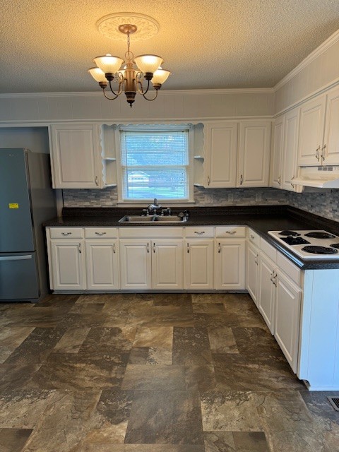 kitchen with white cabinets, a chandelier, sink, and stainless steel fridge