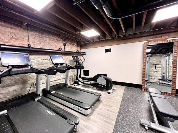 workout area featuring hardwood / wood-style floors and brick wall