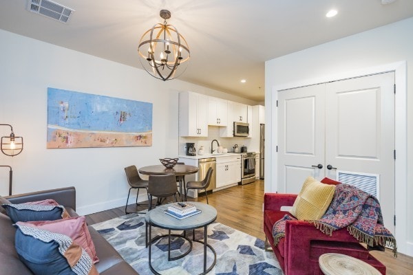 living room featuring light hardwood / wood-style flooring, a chandelier, and sink