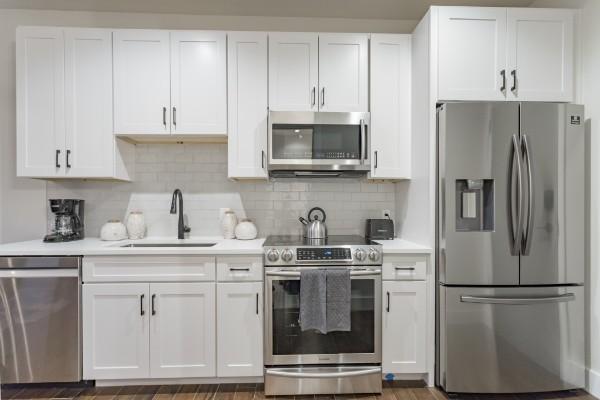 kitchen with appliances with stainless steel finishes, sink, and white cabinets