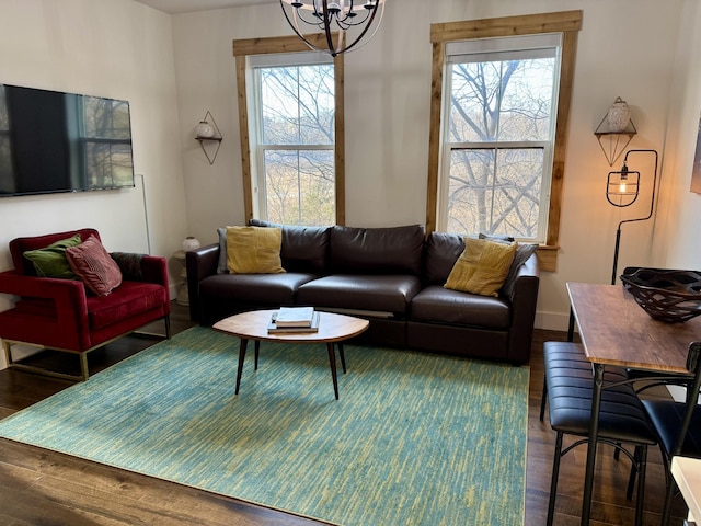 living room with plenty of natural light, dark hardwood / wood-style floors, and a notable chandelier