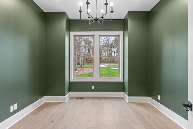 unfurnished dining area with light hardwood / wood-style floors and an inviting chandelier