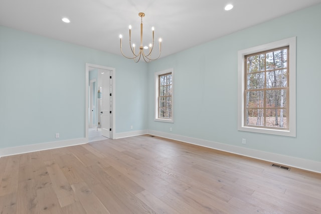 spare room with a notable chandelier and light hardwood / wood-style floors