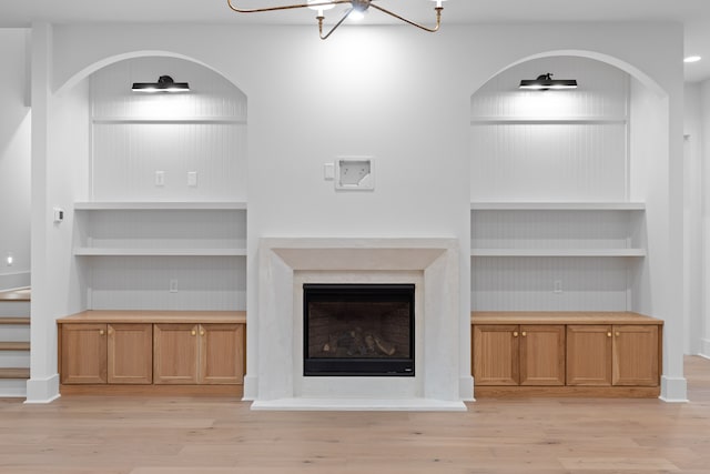 unfurnished living room with a notable chandelier and light wood-type flooring