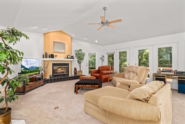 living room featuring ceiling fan, a tile fireplace, vaulted ceiling, and light colored carpet