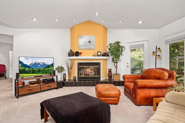 living room with a tiled fireplace, lofted ceiling, and carpet flooring