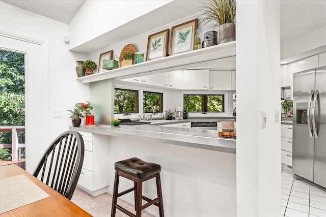 kitchen featuring appliances with stainless steel finishes, a breakfast bar area, light tile patterned floors, and white cabinets