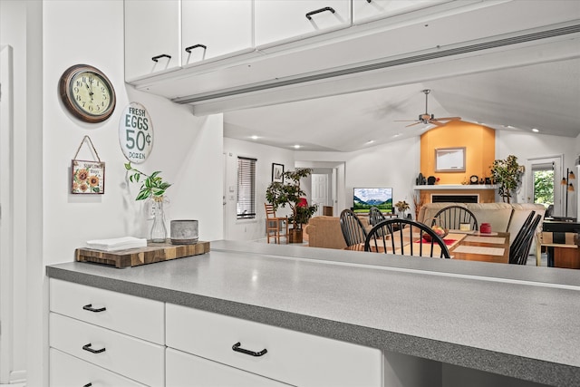 kitchen with lofted ceiling, ceiling fan, and white cabinetry